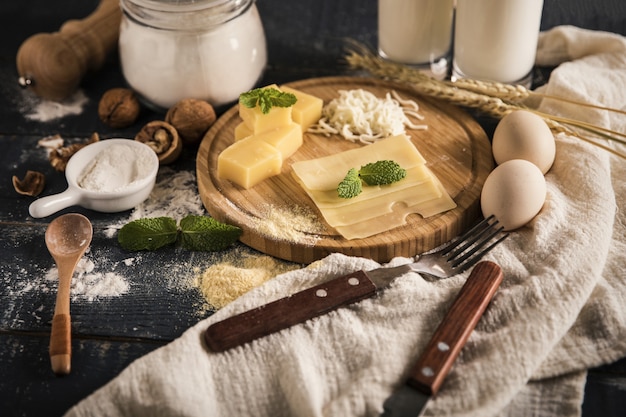 Вид сверху вкусного сырного ассорти с молоком, мукой и яйцами на столе