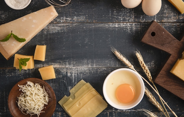 Top view of a delicious cheese platter with walnuts, eggs, and flour on a table with copy space