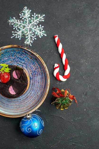 Вид сверху вкусный чизкейк с клубникой и шоколадом на тарелке рождественские детали на темном изолированном фоне