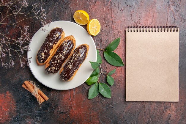 Top view delicious choco eclairs on dark table dessert sweet cake pies