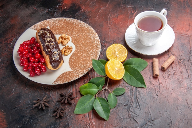 Top view delicious choco eclairs with cup of tea on a dark table pie dessert cake sweet