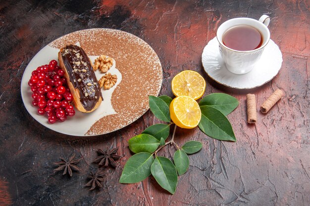 Вид сверху вкусные шоколадные эклеры с чашкой чая на темном столе, пирог, десерт, торт, сладкий