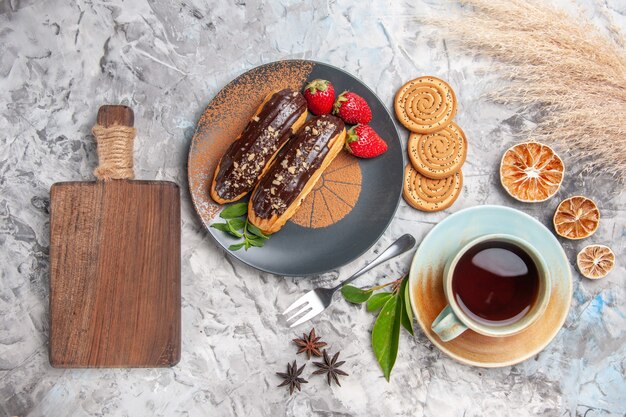 Top view delicious choco eclairs with tea on white floor dessert cake cookie