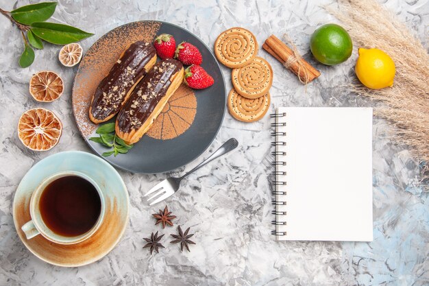 Top view delicious choco eclairs with tea on the white table dessert cake cookie