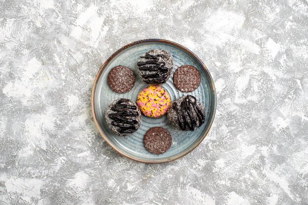 Top view of delicious chocolate balls cakes with cookies on white surface