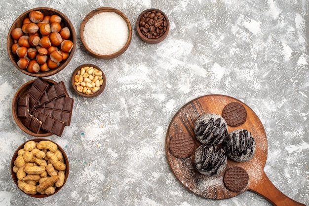 Vista dall'alto di deliziose barrette di cioccolato con nocciole e arachidi sulla superficie bianca