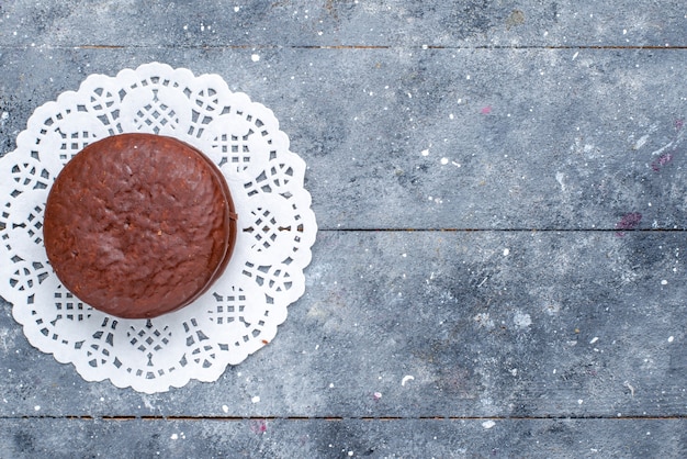 灰色の机の上に孤立して形成されたおいしいチョコレートケーキラウンドの上面図、チョコレートケーキココア甘いビスケットを焼く