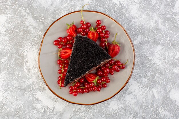 Top view delicious chocolate cake sliced with choco cream and fresh red cranberries on the grey background cake biscuit dough sweet