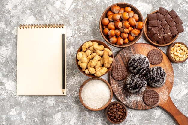 Вид сверху вкусных шоколадных пирожных с печеньем, орехами и арахисом на белой поверхности