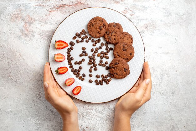 Top view delicious chocolate cookies with chocolate chips and strawberries on the white surface biscuit sugar sweet bake cake cookies