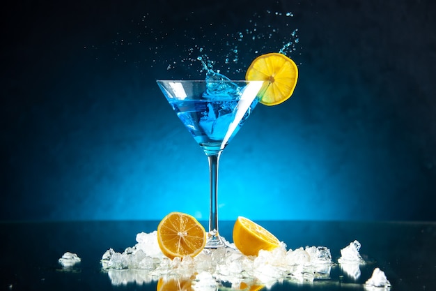 Top view of delicious cocktail in a glass goblet served with lemon slice on blue background