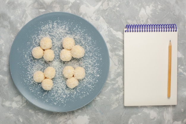 흰색 표면에 메모장 블루 접시 안에 맛있는 코코넛 사탕의 상위 뷰