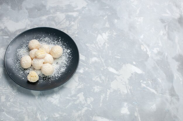 Top view delicious coconut candies inside plate on white