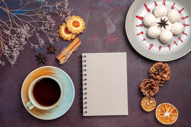 Top view delicious coconut candies little and round formed with cup of tea on dark background coconut candy sweet cake cookie