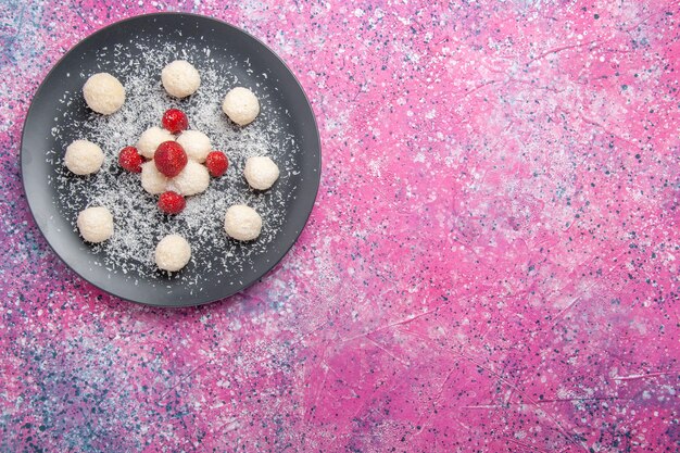 Вид сверху вкусных кокосовых конфет, сладких шариков на розовом полу, конфеты, сахар, сладкий торт, печенье