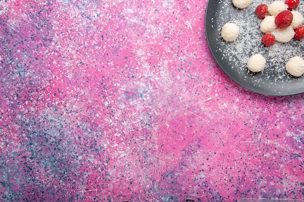 Free photo top view of delicious coconut candies sweet balls on pink surface