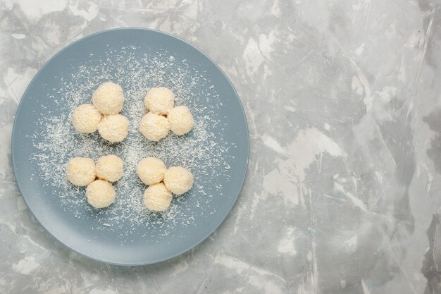 Foto gratuita vista dall'alto di deliziose palline dolci di caramelle al cocco sulla superficie bianca