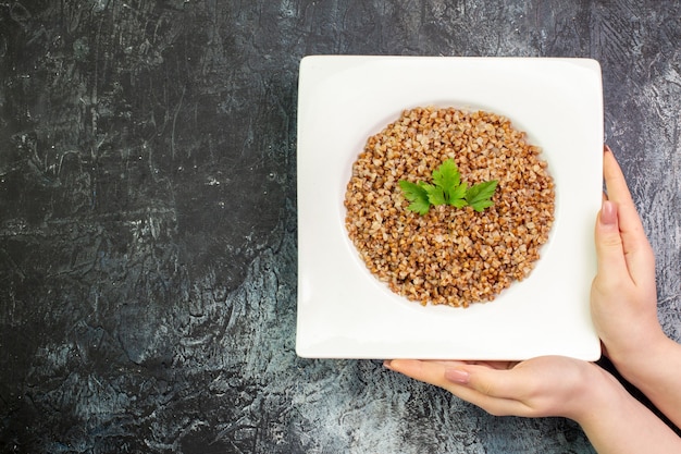 Free photo top view delicious cooked buckwheat inside plate on light-grey background calorie food meal color photo dish bean