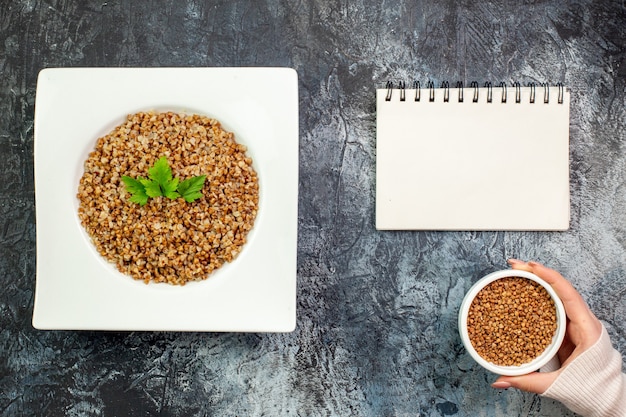 Free photo top view delicious cooked buckwheat inside plate on a light-grey background calorie meal color photo dish bean food