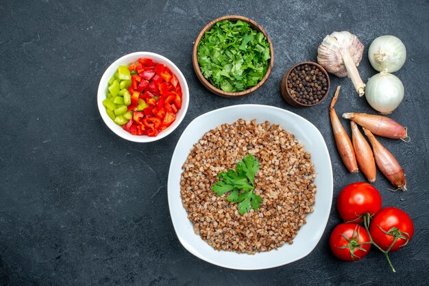 Top view delicious cooked buckwheat with tomatoes and greens on grey space