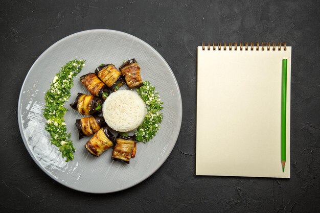 Top view delicious cooked eggplants with greens and rice on a dark surface dinner food cooking oil rice meal