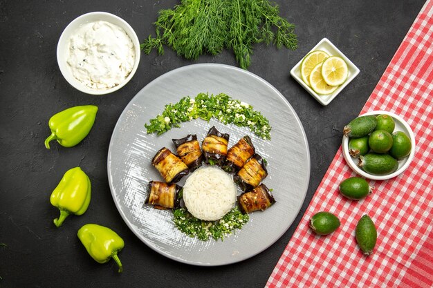 Вид сверху вкусные приготовленные баклажаны с рисом и фейхоа на темной поверхности обеденная еда, готовящая рисовую муку