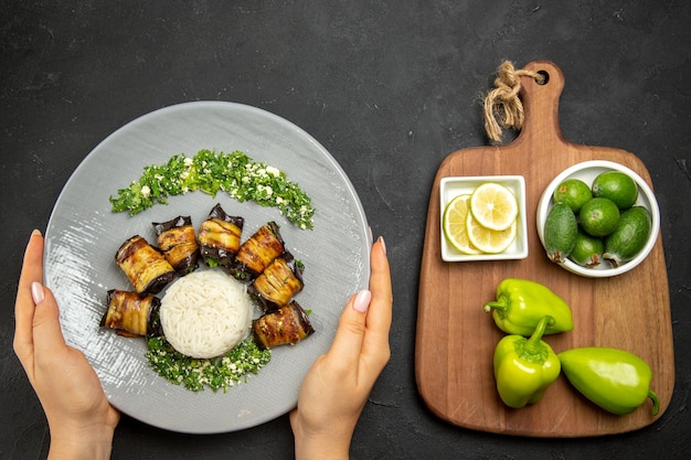 Top view delicious cooked eggplants with rice lemon slices and feijoa on dark surface dinner food cooking oil rice meal