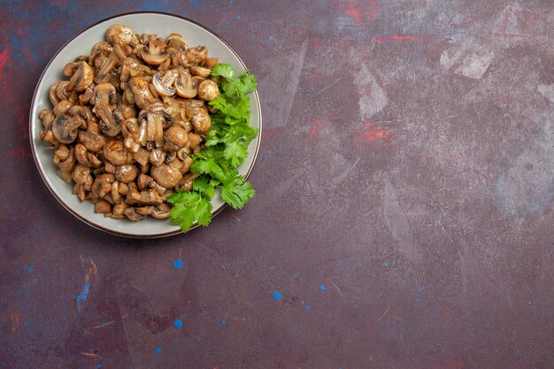 Top view delicious cooked mushrooms with greens on the dark background meal dish dinner wild plant food