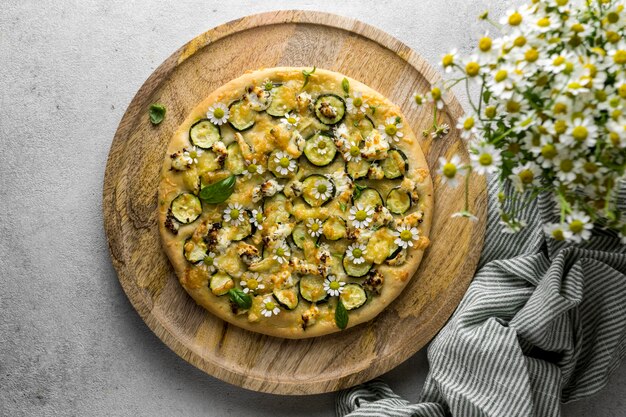 Top view of delicious cooked pizza with bouquet of chamomile flowers