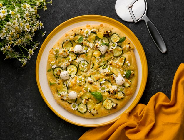 Top view of delicious cooked pizza with chamomile flowers and pizza cutter