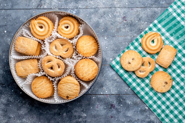 Top view of delicious cookies different formed inside round package on grey desk, sugar sweet cake biscuit cookie