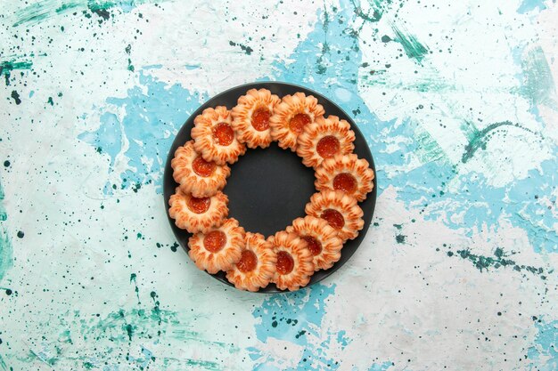 上面図水色の背景に黒いプレートの内側にジャムで形成されたおいしいクッキーラウンドクッキーシュガースイートビスケットケーキ