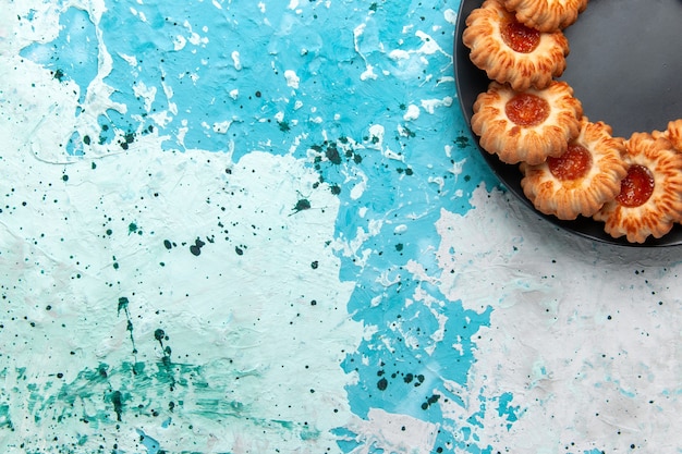 Бесплатное фото Вид сверху вкусного печенья круглой формы с джемом внутри черной тарелки на голубом фоне печенье сахарный сладкий бисквитный торт