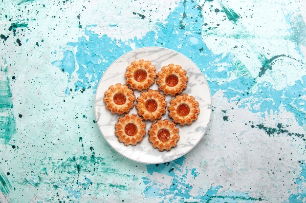 Top view delicious cookies round formed with jam inside plate on light blue background cookie sugar sweet biscuit dough cake bake