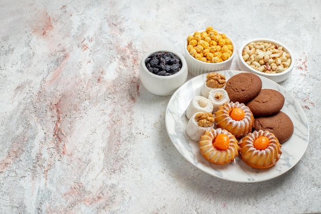 Вид сверху вкусное печенье с конфетами и орехами на белом фоне сладкий торт печенье бисквитный орех