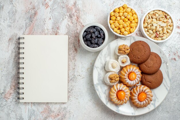 Top view delicious cookies with candies and nuts on white desk sweet cake cookie biscuit nut