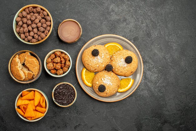 Top view delicious cookies with chips and nuts on dark-grey desk cookie biscuit tea sweet cake