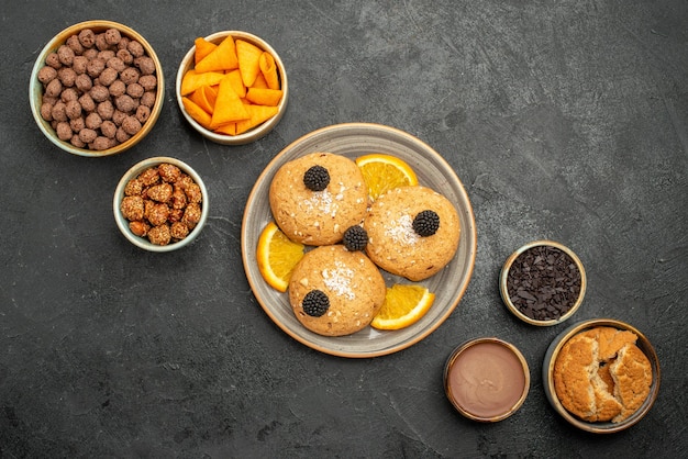 Top view delicious cookies with chips and nuts on dark-grey surface cookie biscuit tea sweet cake