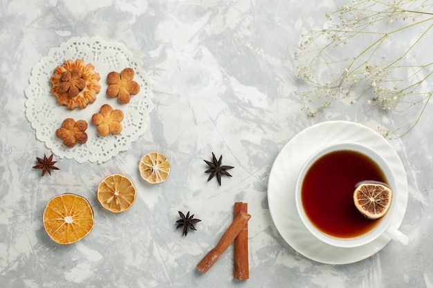 Top view delicious cookies with cinnamon and cup of tea on the light white desk cookie biscuit sugar sweet tea crisps