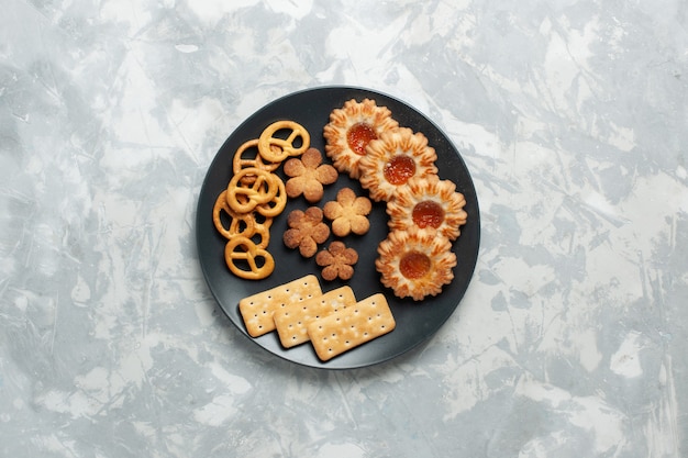 Top view delicious cookies with crackers and crisps inside plate on light-white desk cookie biscuit sugar sweet tea crisp