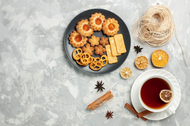 上面図クラッカーとポテトチップスが入ったおいしいクッキーと白い机の上のお茶