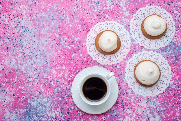 着色された机の上のクリームと一杯のコーヒーと上から見るおいしいクッキークッキークリーム砂糖甘い