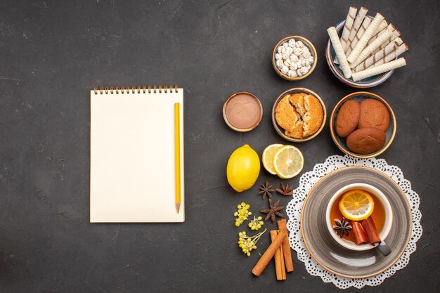 Vista dall'alto deliziosi biscotti con una tazza di tè sul biscotto scuro della scrivania biscotto agli agrumi dolce zucchero alla frutta