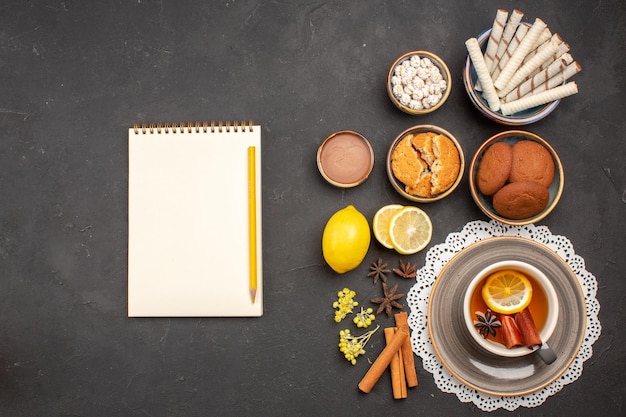 Top view delicious cookies with cup of tea on dark desk cookie sweet citrus biscuit fruit sugar