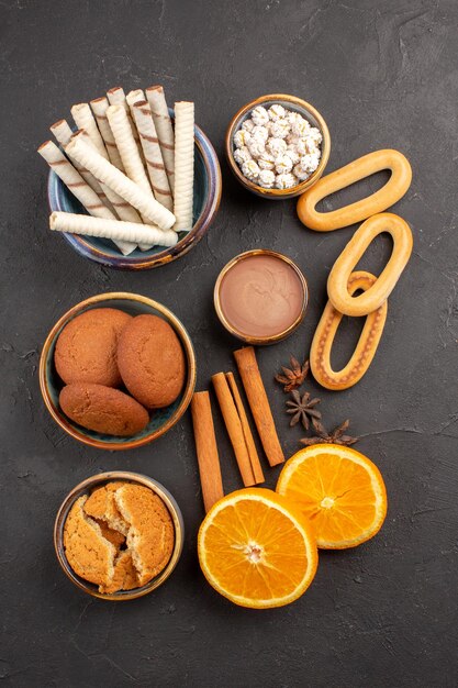 Top view delicious cookies with fresh oranges on dark surface cookie sweet citrus biscuit fruit sugar