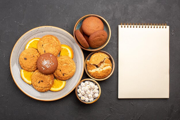 Вид сверху вкусное печенье со свежими нарезанными апельсинами на темном фоне печенье торт фруктовый сладкий цитрусовый бисквит