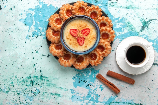 Vista dall'alto deliziosi biscotti con marmellata di caffè e dessert alla fragola sulla superficie blu