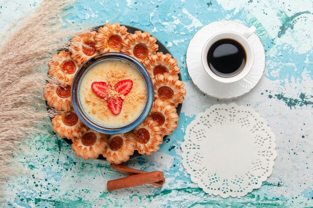 Top view delicious  cookies with jam cup of coffee and strawberry dessert on the blue surface