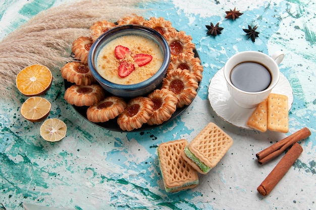 밝은 파란색 표면에 잼 커피와 딸기 디저트가 있는 맛있는 쿠키