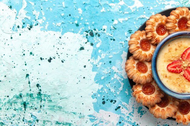 Вид сверху вкусного печенья с джемом и клубничным десертом на синем фоне, печенье, сахар, сладкий бисквитный торт